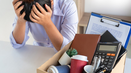 Stress of business woman packing brown cardboard box her belonging after resign and signing cancellation contract letter, Change of job unemployment or resignation concept.