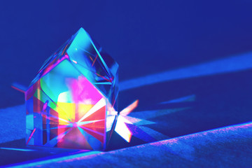  Closeup of colorful glass prism house on trendy blue background with rainbow light refraction and...