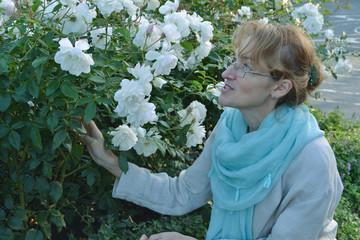  A young woman is enjoying roses in a park. The beauty and aroma of flowers give her voluptuous...