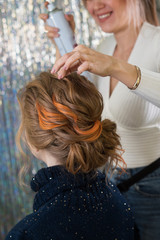 Fototapeta premium Hairdressing services. Creation of evening hairstyles fashionable stylish women's hairstyles. Hair styling process. Hairtician fixes hair with hair spray. Back view. Elegant colored hairstyle. Trendy