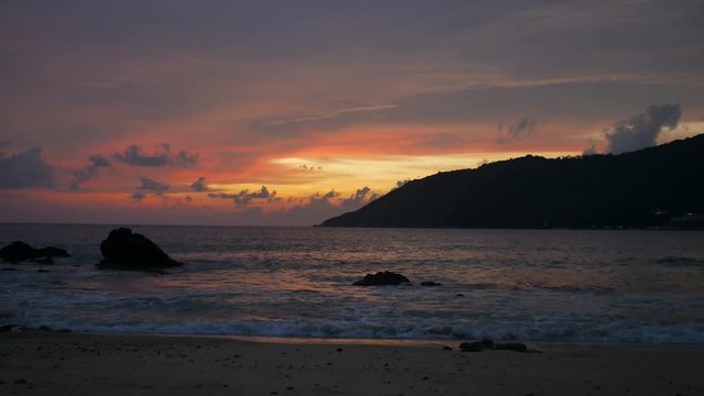moving sea wave hit rock and sand sea in twilight yellow orange colorful cloudy sky in evening and silhouette cape mountain.