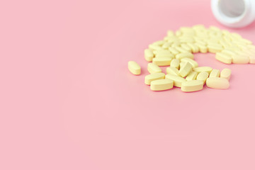 Many yellow tablets pills medicine medical on pink background. Medicines, tablets, capsules, drug of painkillers, antibiotics, vitamins and small bottle. Health care medical.
