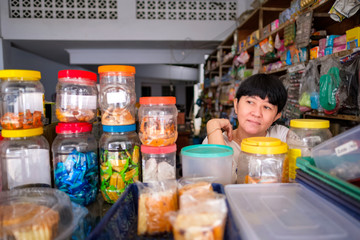 Asian Indonesian women in front of small local family-owned business store, locally called warung. Selective Focus.