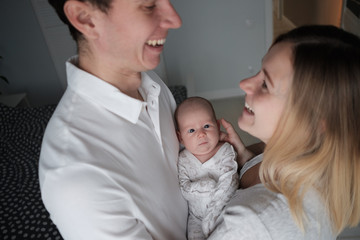 Smiling mother and father holding their newborn baby daughter at home