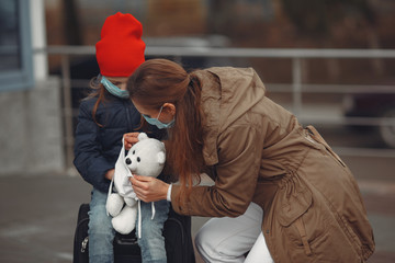 Obraz na płótnie Canvas A European mother in a respirator with her daughter are standing near a building.The parent is teaching her child how to wear protective mask to save herself from virus.
