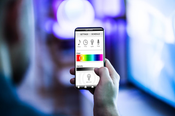 Human Hand Adjusting Electric Light Through Mobile Phone