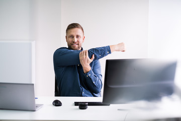 Close-up Of Businessman Stretching His Hands At Workplace