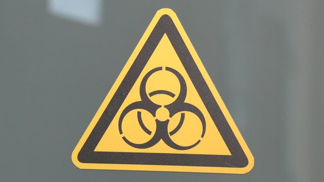 Biohazard symbol sign of biological threat alert. The sign on the door is “Caution. Biohazard (Infectious Substances)”.