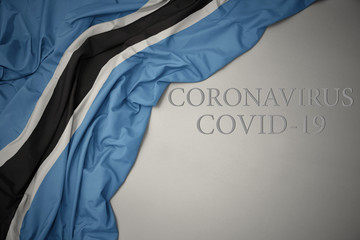 waving national flag of botswana on a gray background with text coronavirus covid-19 . concept.