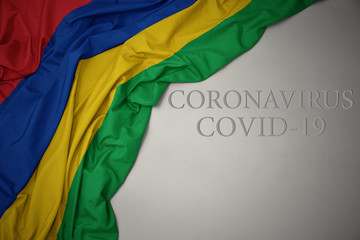 waving national flag of mauritius on a gray background with text coronavirus covid-19 . concept.
