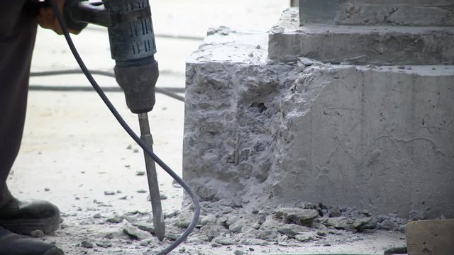 Worker man mason drilling cement concrete floor with machine. Builder worker pneumatic hammer drills hole in concrete brick wall with diamond crown for electric cable.