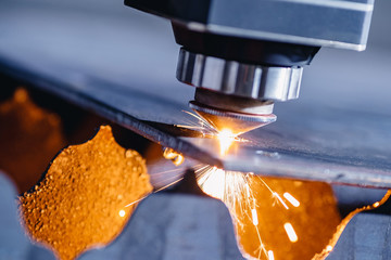 CNC laser machine cutting sheet metal with light spark. Technology plasma industrial, Blue steel...
