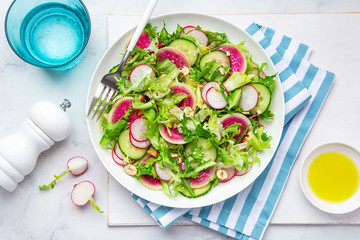 Fresh vegan watermelon radish and  cucumber salad on white plate