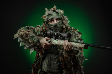 sniper in a poncho camouflage suit and a sniper rifle