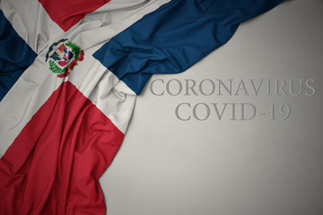 waving national flag of dominican republic on a gray background with text coronavirus covid-19 . concept.