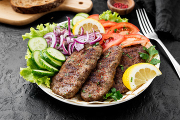Grilled meat kebabs (cutlets) served with vegetables and tortilla, flatbread. 