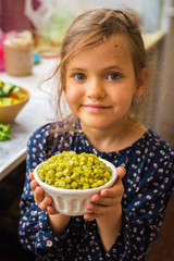 Little young vegan, vegetarian girl kid with food in hands. Healthy eating. Family  health care concept. Green peas cooked