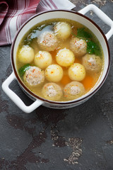 White bowl with meatball and potato soup, high angle view on a brown stone background with space
