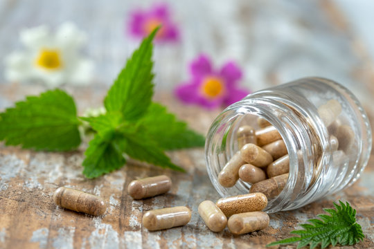 Bottle of pills food suplements healthy medicine medication health care treatment additives pharmacy with medicinal fresh plants and flowerson background