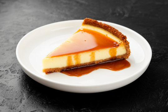 Cheesecake slice with caramel sauce on white plate . black background