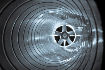 closeup view from inside the galvanized steel air duct on the exhaust fan in the background light, the front and back background is blurred with a bokeh effect - obrazy, fototapety, plakaty