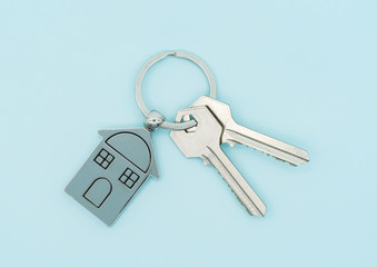 key chain with house symbol and keys on blue background,Real estate concept