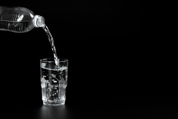  pouring water into a glass on a dark background