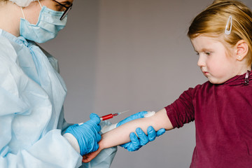 Obraz premium Doctor, nurse in a protective suit and mask taking blood sample in syringe from patient at laboratory. Sample COVID-19 test. Epidemic Coronavirus. Conduct laboratory test - Positive result.