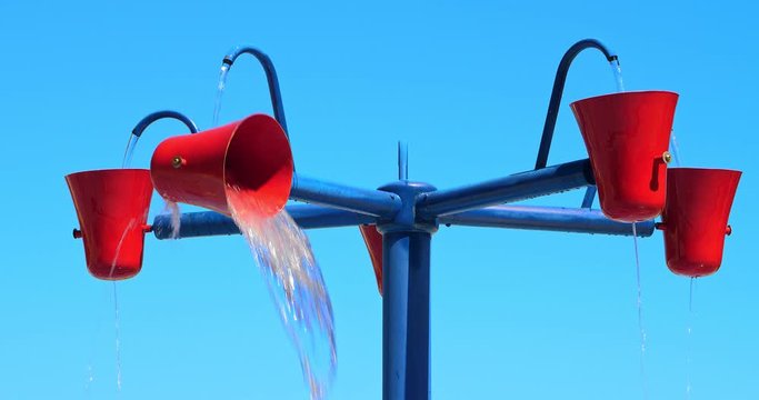 Buckets spilling splashing water at kids at amusement park, 4K