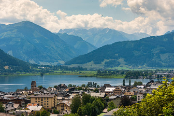 Fototapeta na wymiar Cityscape of alpine city Zell am See with Zeller Lake in summer. Above view of Tirol lake, meadows and Tirol Alps Mountains in Austria.