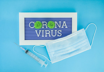 coronavirus letters on blue background,Respiratory protection mask next to the syringe,Health care and medical concept.