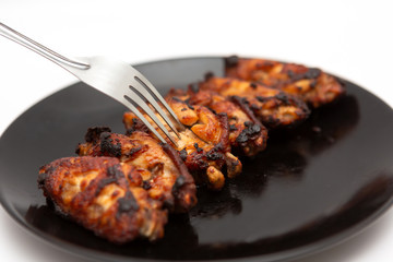 barbecue chicken wings close up on wooden tray shot with selective focus In the black plate, white background
