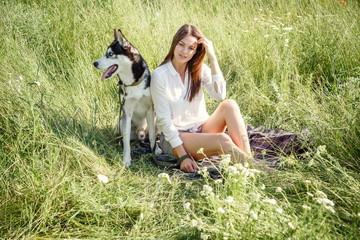 Naklejka na ściany i meble Beautiful woman playing with husky dog outdoors at park.