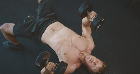 Strong muscular man lifting weights in the gym, weightlifter doing dumbbell presses and achieving his fitness goals - Powered by Adobe