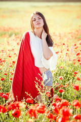 young beautiful woman walking through a poppy field