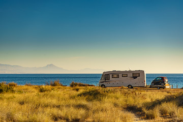 Camper on beach with little car on platform