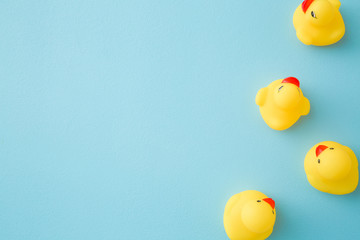 Yellow rubber ducklings. Top view. Empty place for text on light blue background. Pastel color.