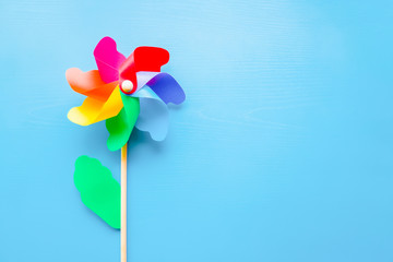 Colorful plastic toy windmill propeller flower for kids on blue background. Empty place for positive text, quote or sayings. Top down view. Closeup.