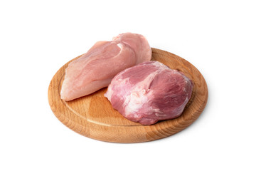 Raw pork meat and chicken fillet on wooden board isolated on white background.
