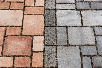 Red and gray brick paving stones on a sidewalk. Separation of bike and footpath