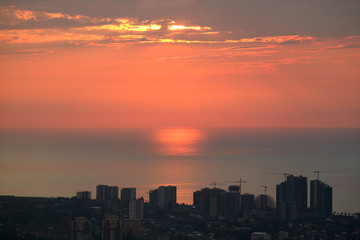 Stunning view of the setting sunlight reflection on the sea with group of skyscrapers in foreground