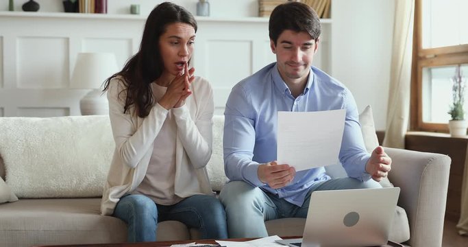 Frustrated young adult couple feeling stressed about high mortgage rates doing paperwork at home. Angry husband and wife renters calculating household payments, having financial problems or bank debt.