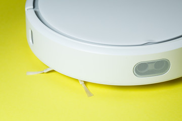 white robot vacuum cleaner for cleaning the house on a yellow background