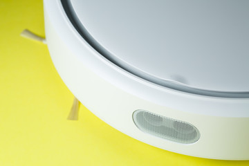 white robot vacuum cleaner for cleaning the house on a yellow background