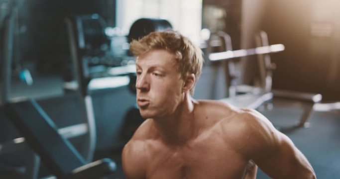 Attractive muscular man working out in the gym lifting a kettlebell, intense weight lifter with amazing body achieving his fitness goals