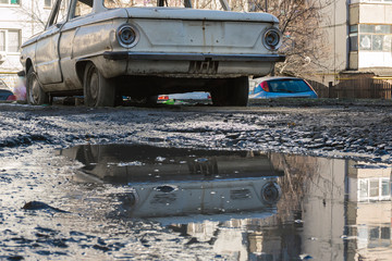 an old wrecked car in a muddy puddle abandoned stands