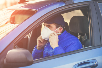 A man in medical face mask (respirator) during an epidemic in the car
