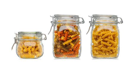 Pasta in three glass jars isolated on a white background.