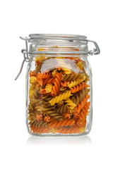 Tricolor fusilli pasta in a glass jar isolated on white background.
