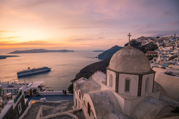 Beautiful summer landscape, luxury travel background. Amazing evening view of Fira, caldera, volcano of Santorini, Greece with cruise ships at sunset. Cloudy dramatic sky.